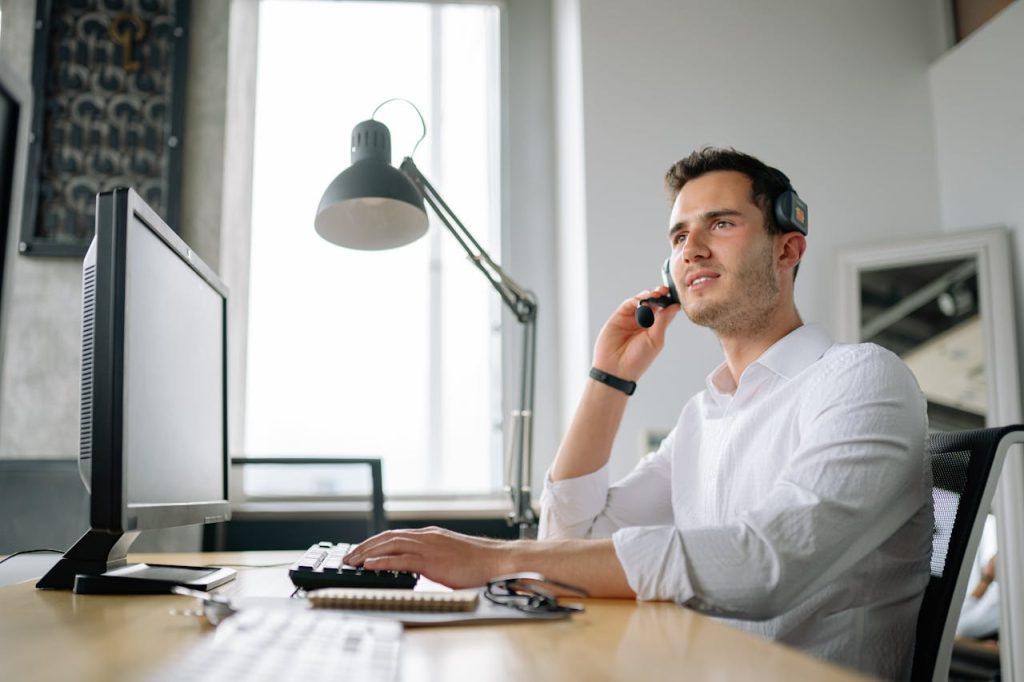 a-man-working-in-a-call-center-8867431 Male call center agent with headset working at desk, providing excellent customer service.
